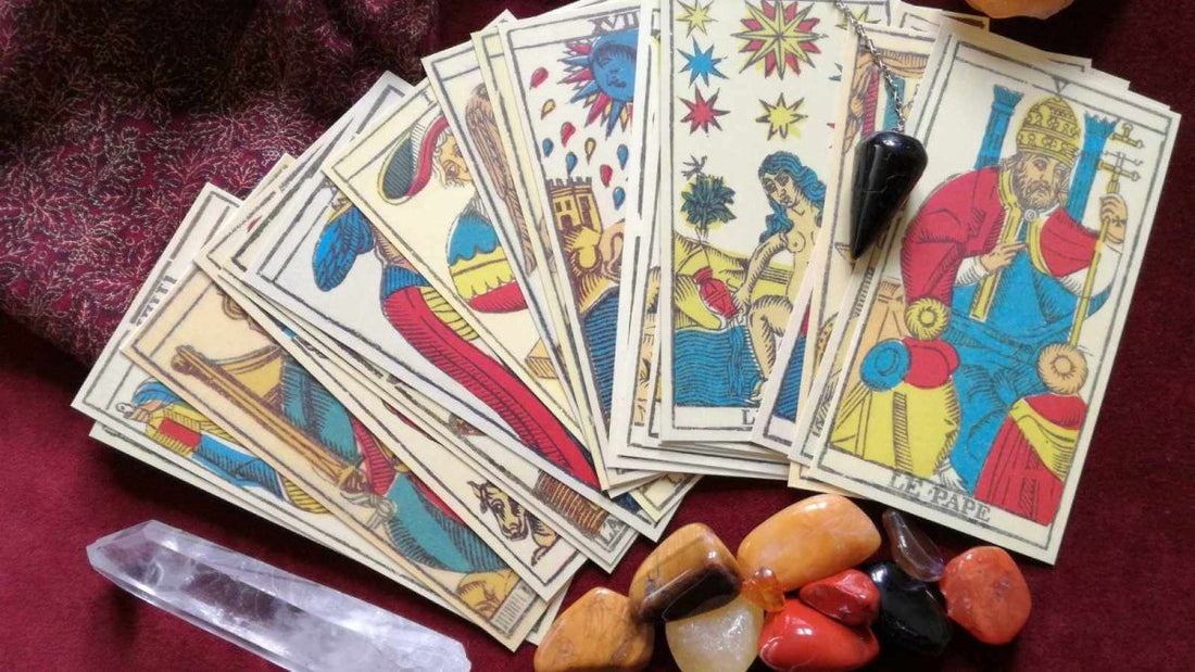 Tarot cards spread out on a red background. Next to the Tarot cards are various crystals, including a Clear Quartz wand.