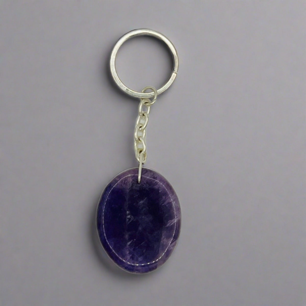 An oval shaped Amethyst crystal attached to a silver keyring chain.