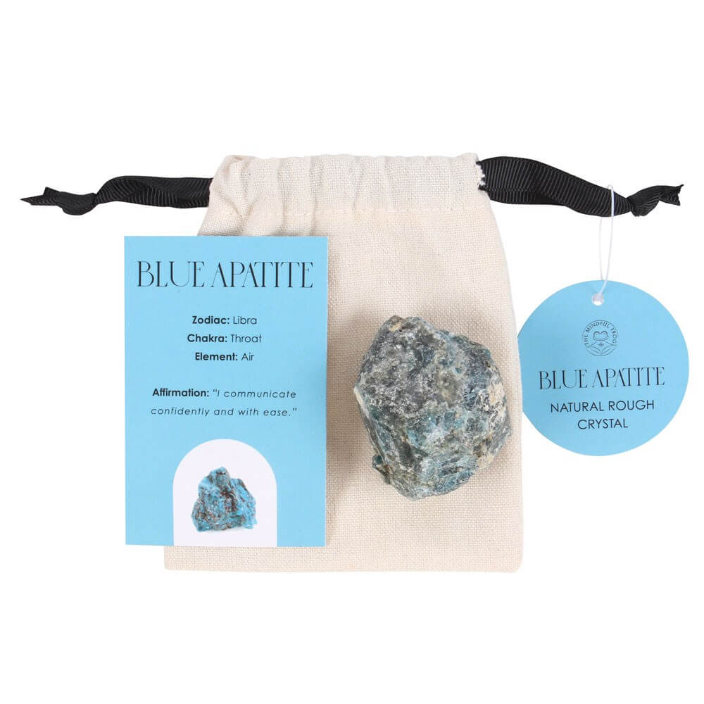 A chunk of Blue Apatite crystal on top of a cotton drawstring bag, next to an information card.