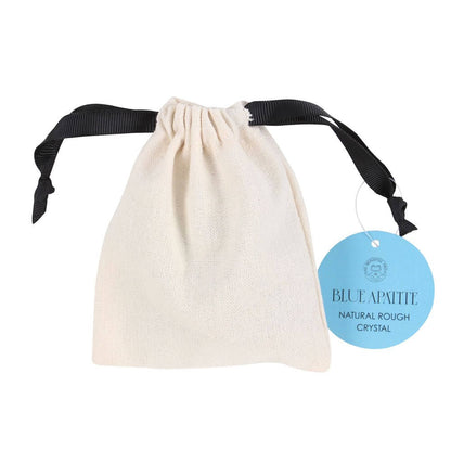 A cotton drawstring pouch that has a label stating Blue Apatite natural rough crystal. The bag is against a white background.