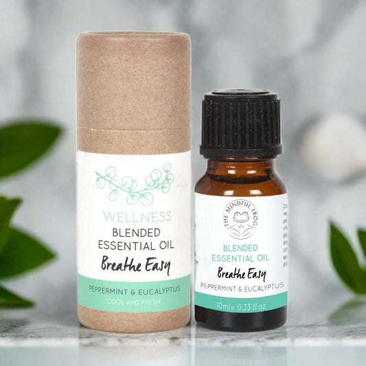 Cardboard essential oil bottle packaging, with a white and green label, next to a 10ml brown bottle of essential oil.