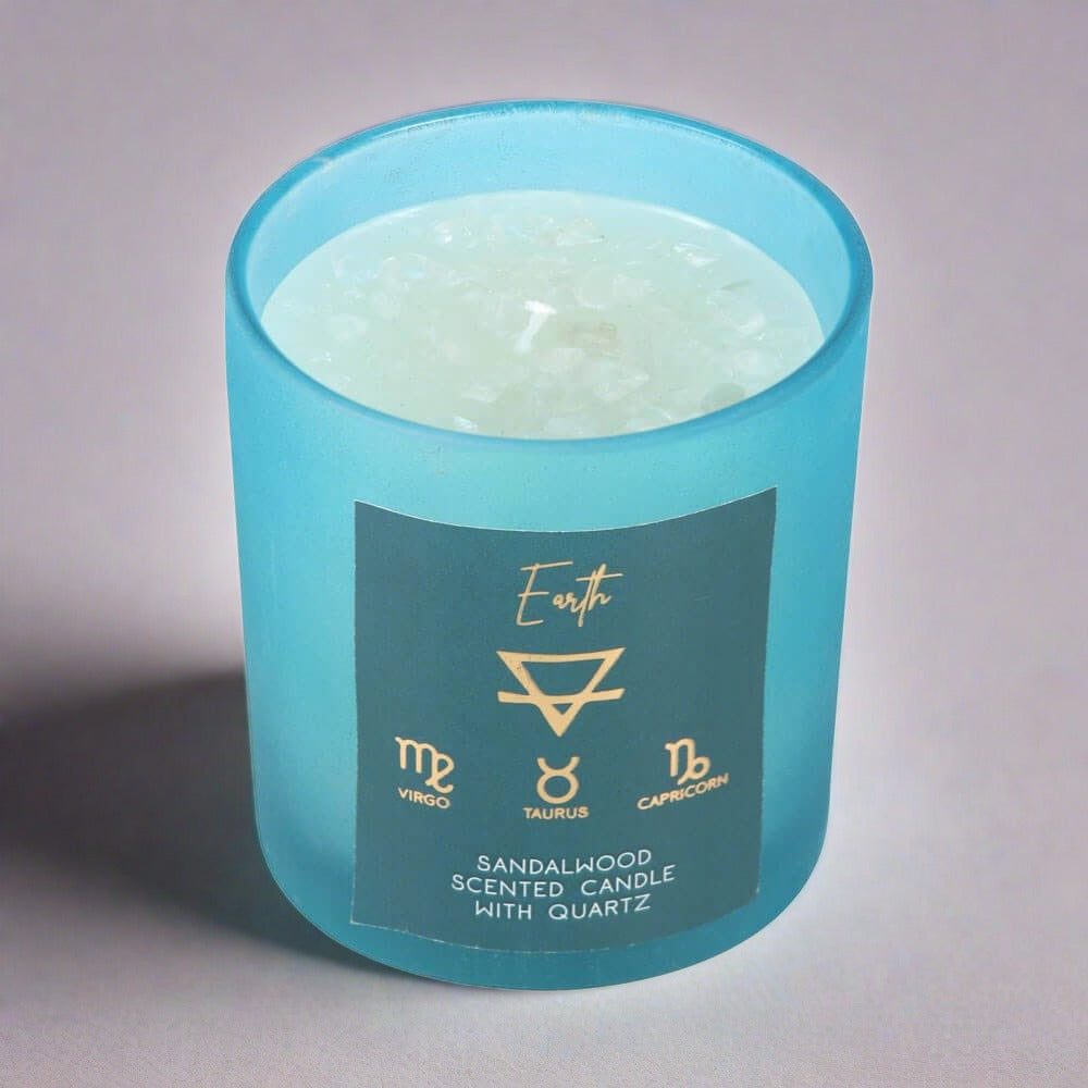 A light blue candle in a jar that has Clear Quartz crystal chips in. Includes the words Virgo, Taurus and Capricorn.