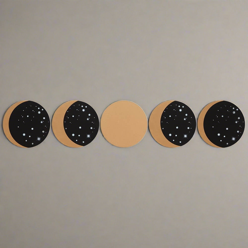 A top view of the five black and gold homeware drink coasters. Each shows a different phase of the moon.