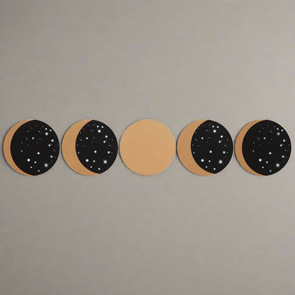 A top view of the five black and gold homeware drink coasters. Each shows a different phase of the moon.