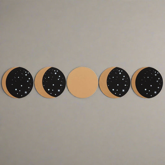 A top view of the five black and gold homeware drink coasters. Each shows a different phase of the moon.