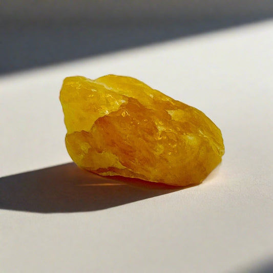 A chunk of rough orange Calcite crystal on a white background.